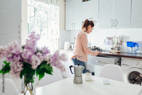 Woman cooking dinner and having coffee on the kitchen. Modern kitchen design. © maryviolet