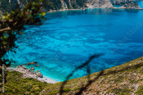 Myrtos beach with azure blue sea water in the bay with dark pattern on bottom. Favorite tourist visiting destination location at summer on Kefalonia island, Greece, Europe