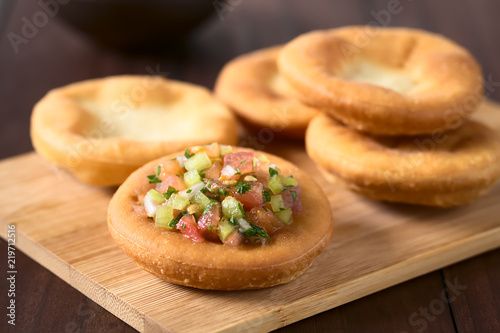 Traditional Chilean Sopaipilla fried pastries, one served with Chilean pebre salsa, photographed with natural light (Selective Focus one third into the pebre sauce on the sopaipilla) photo
