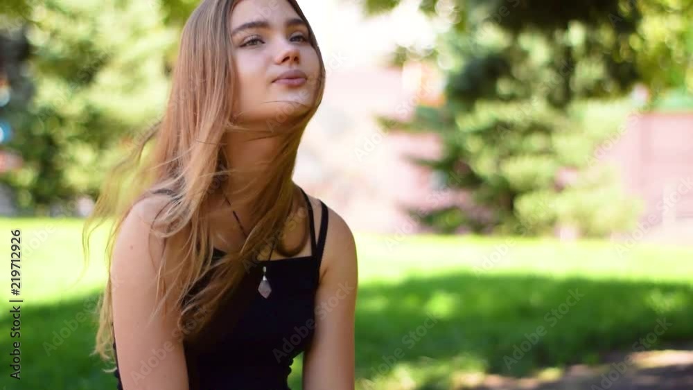 Lovely teenage girl with straight long blonde hair sitting in parkland Lovely teenage girl with straight long blonde hair sitting in parkland