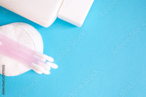 top view personal care products. white bottle, razor, ear sticks, cotton pads, toothbrush on blue background. copy space