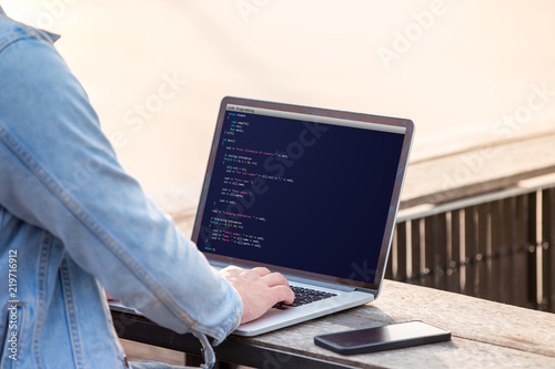 A man is working using laptop doing coding and programming for web development and web design concept at outdoor