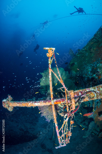 A large, coral encrusted underwater shipwreck in a tropical ocean