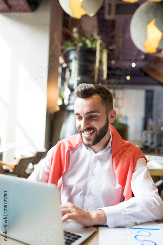 Portrait of smiling young entrepreneur using laptop while working in cafe, copy space