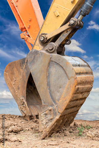 Close shovel or scoop of a backhoe with cloudy skies. photo