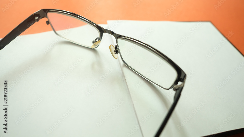 glasses with notebook on orange background.Close up glasses with notebook on orange background.Close up