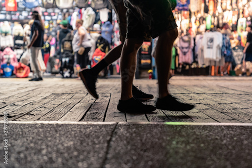 People Walking On Wildwood New Jersey Boardwalk at Night with Apparel store in Background and Man Walking in Sandals in Foreground