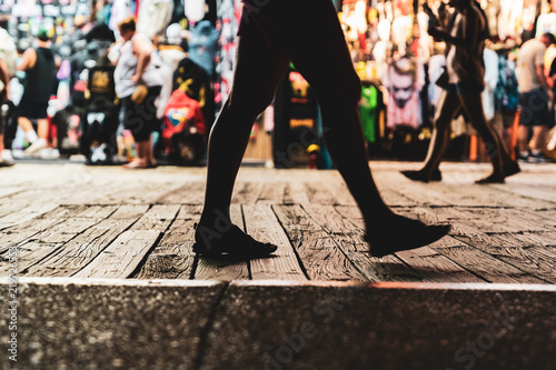 People Walking On Wildwood New Jersey Boardwalk at Night with Apparel store in Background and Man Walking in Sandals in Foreground