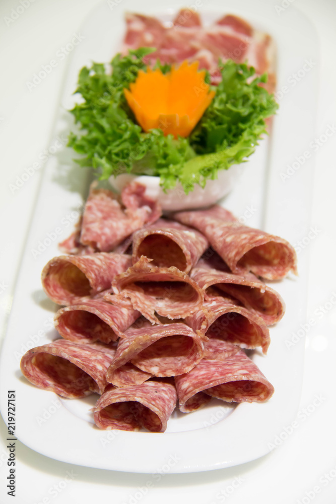 Salami sausage slice and vegetables on plate