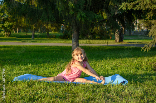 Cute girl do exercises on the lawn in the park