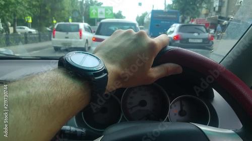 Man's hand with a clock on the steering wheel