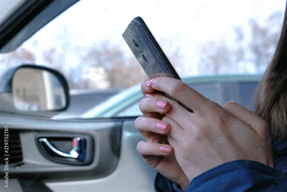 Woman in a car with a mobile phone. Closeup woman's hands chatting in phone. Woman in a car with a mobile phone. Closeup woman's hands chatting in phone.