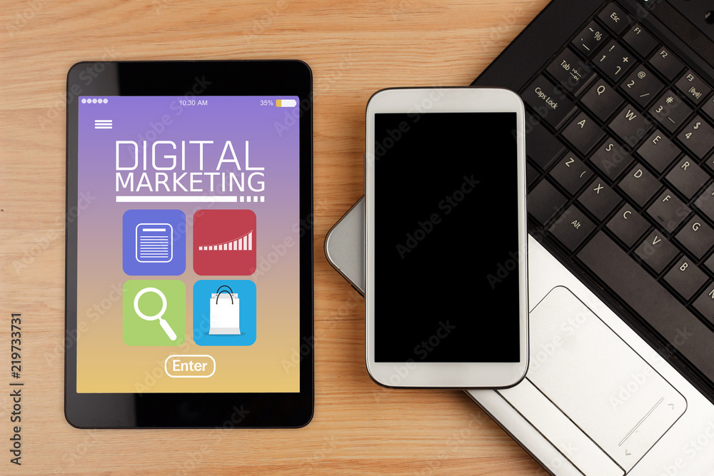 Digital tablet with text DIGITAL MARKETING on screen with office supplies on wooden desk Digital tablet with text DIGITAL MARKETING on screen with office supplies on wooden desk