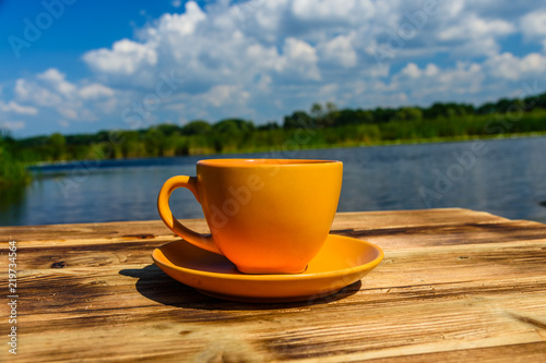 Cup of coffee on wooden table at the riverside