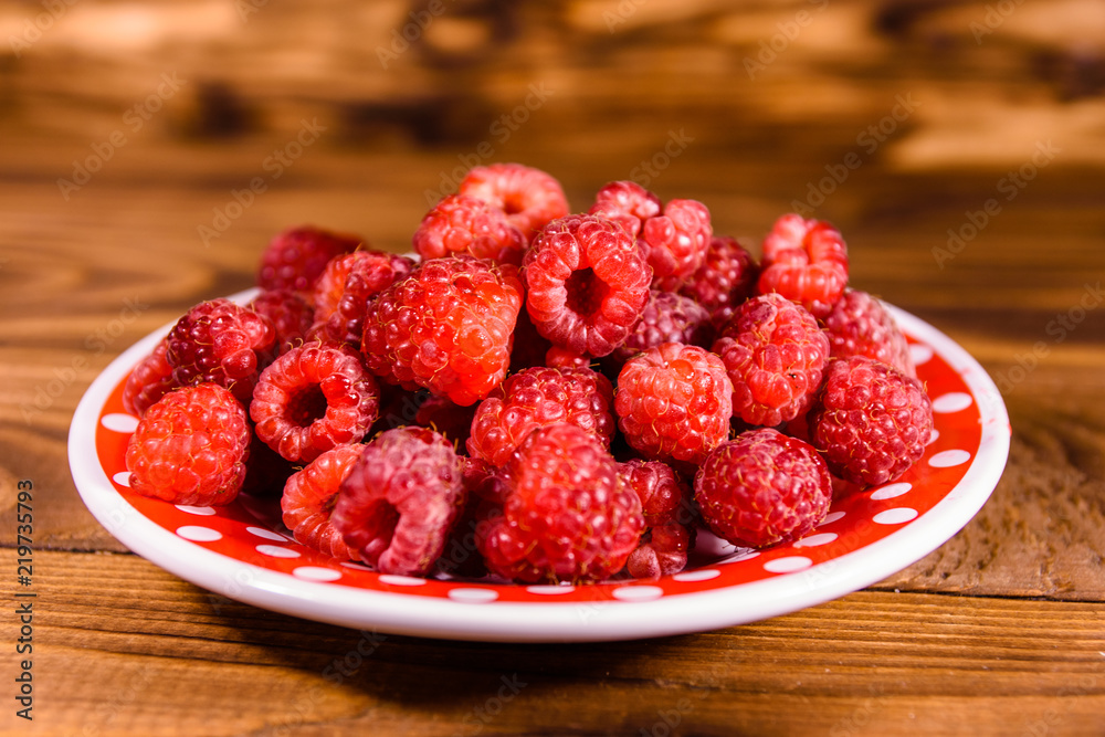 Ceramic plate with ripe raspberries on wooden table Ceramic plate with ripe raspberries on wooden table