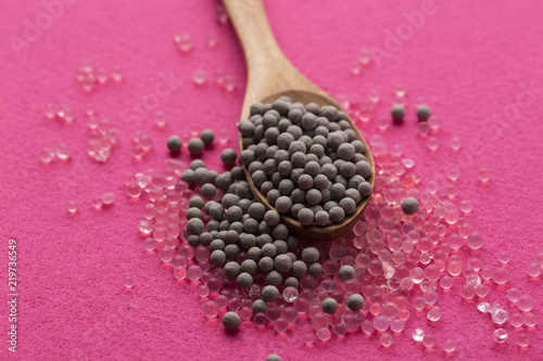 Pile of silica gel on spoon whih pink background, Desiccant used in industrial. moisture protection photo