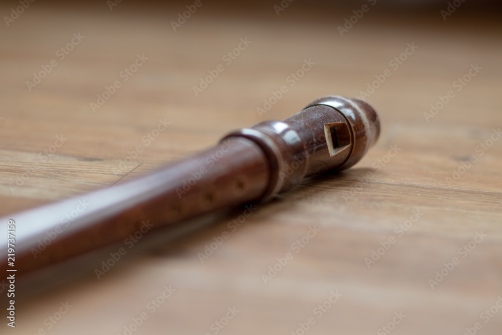 Close of view of a brown wooden recorder lying on the wooden floor