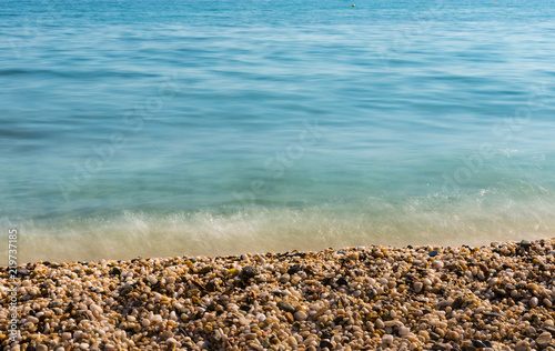 Waves of the blue sea quietly crashing onto a pebble beach in Maronia, Rodopi, Greece photo