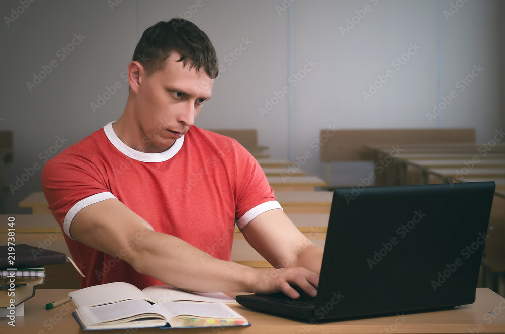 Serious student boy working on a laptop computer and prepare for exam. Serious student boy working on a laptop computer and prepare for exam.