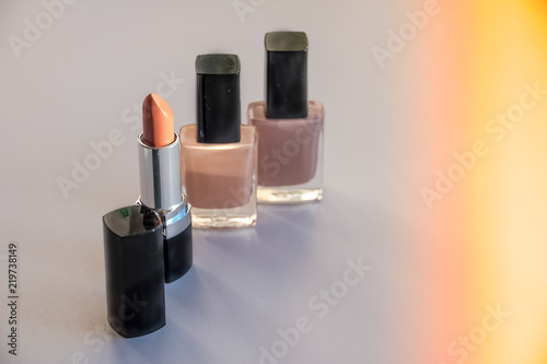 Various Cosmetics isolated on white background. Sun rays. Copy space.Decorative cosmetics.Fashion colors concept.Nude makeup.Selective focus.Nail polish,nail varnish bottles and beige lipstick. © Yulia