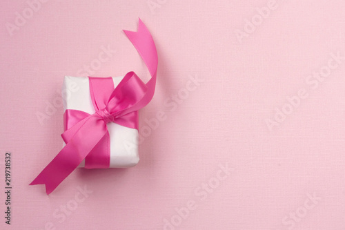 wrapped gift box with pink bow  on paper texture background
