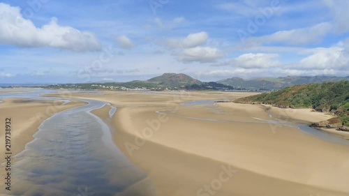 Aerial view, rise and pan move. Drone panorama over low tide sea and sand. Green hills and Borth-y-Gest, Porthmadog and Porthmeirion in Wales