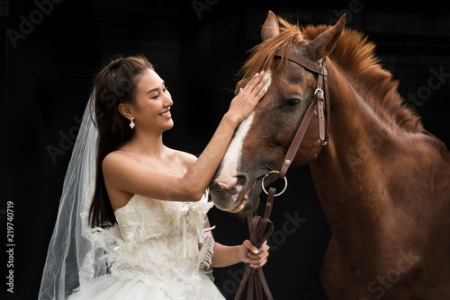 portrait of a beautiful young asian woman bride and brown horse