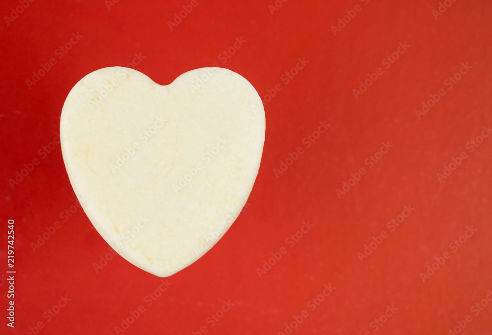 Fototapeta premium White heart from soap on a red background.