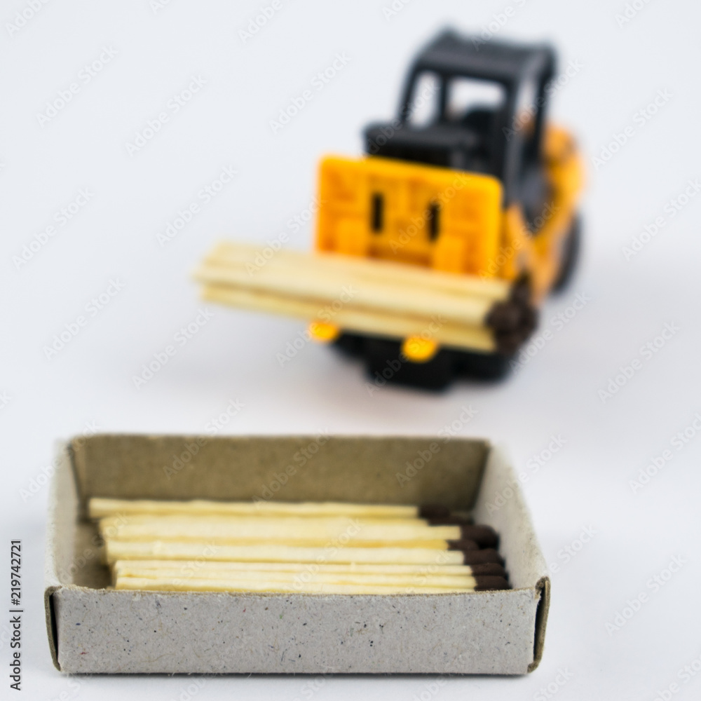 forklift truck with with matches loads into a matchbox on a light background. forklift truck with with matches loads into a matchbox on a light background.
