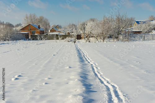 Winter landscape with pedestrian path through snow covered field in Ukrainian village Novoaleksandrivka near Dnipro city
