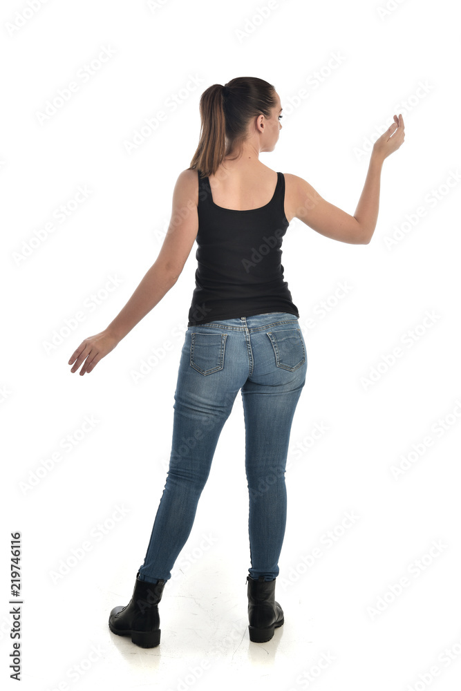 full length portrait of brunette girl wearing black single and jeans. standing pose with back to the camera. isolated on white studio background. full length portrait of brunette girl wearing black single and jeans. standing pose with back to the camera. isolated on white studio background.