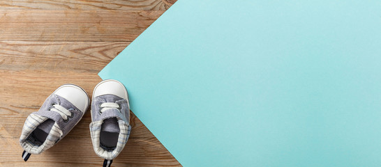 Baby boy shoes on pastel blue and wooden background, banner