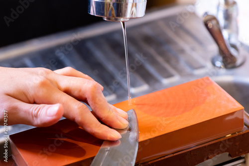 Schilderij op canvas woman professional chef hands hold knife for whetting on whetstone