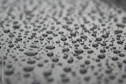 Water rain drops bakground over black surface texture. Beautiful texture of rain drops.