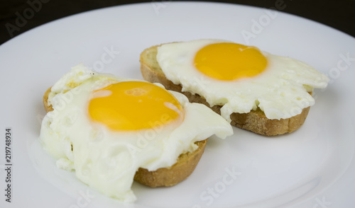 Two sandwiches with egg on a white plate.