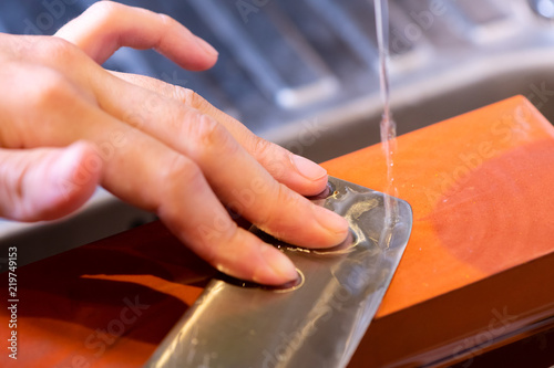 фотографія woman professional chef hands hold knife for whetting on whetstone