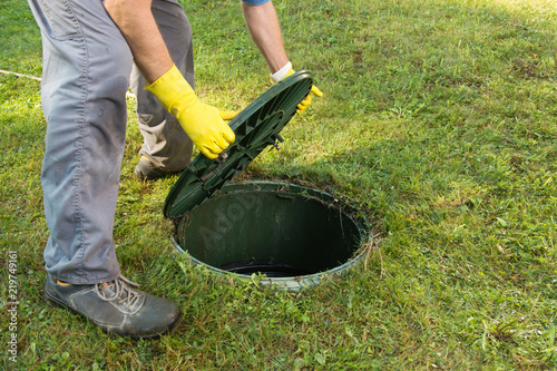 Opening septic tank lid. Cleaning and unblocking septic system and draining pipes.........