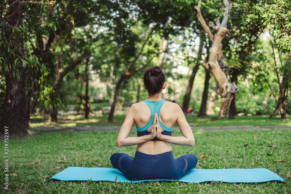 Fototapeta premium Woman doing yoga pose/meditation at outdoor green park/garden with happy feeling in the morning