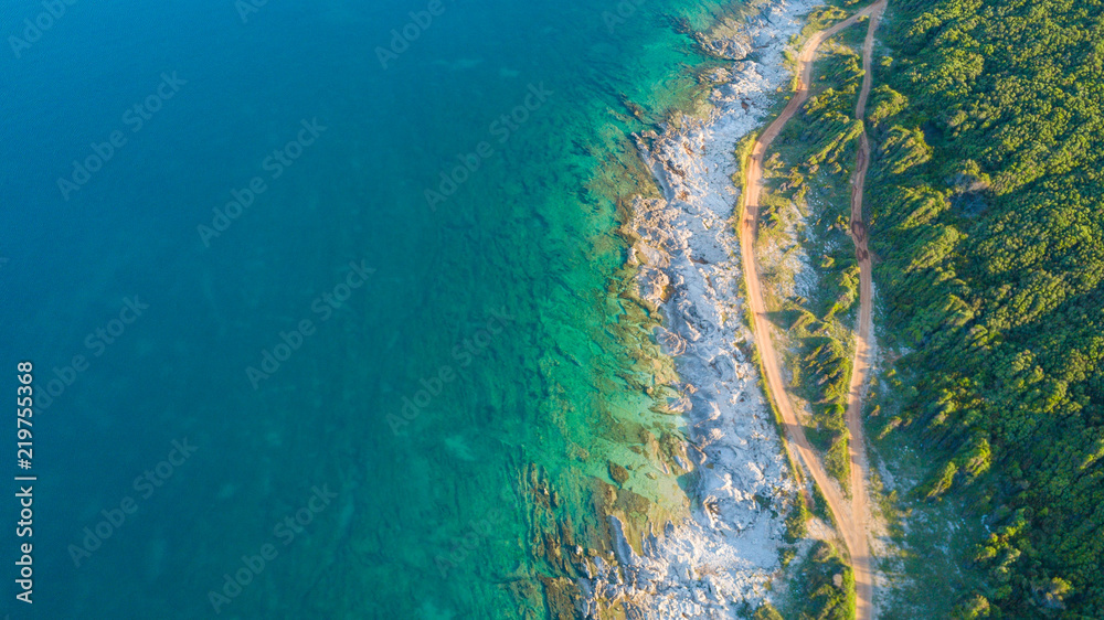 Fototapeta premium Drone shot of a rocky headland at daylight with emerald color water