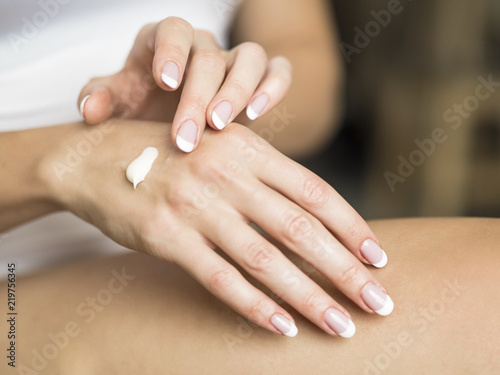 Woman applies cream on her hands. Close up.