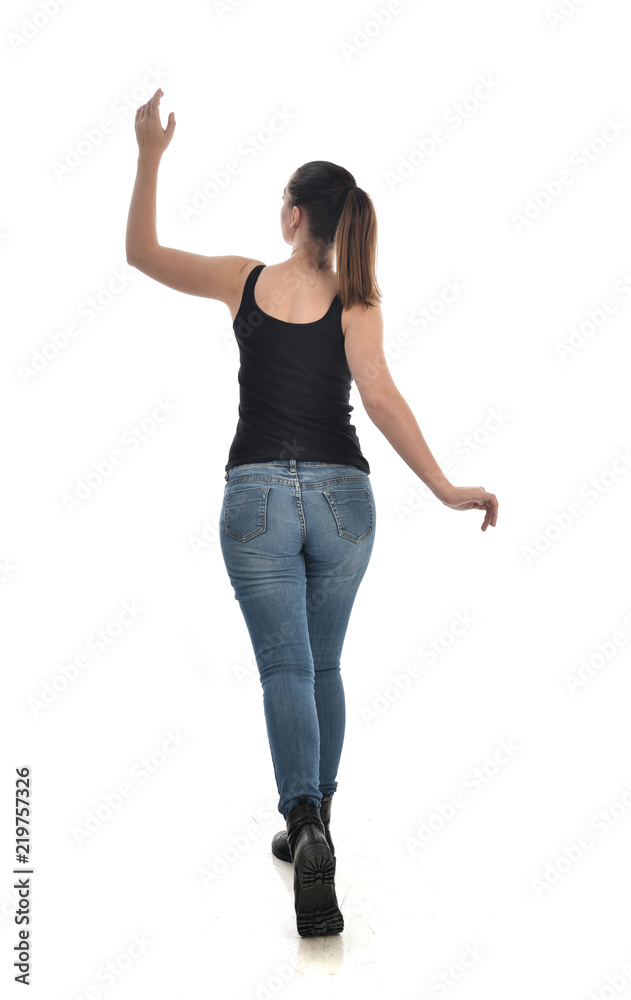 full length portrait of brunette girl wearing black single and jeans. standing pose with back to the camera. isolated on white studio background. full length portrait of brunette girl wearing black single and jeans. standing pose with back to the camera. isolated on white studio background.