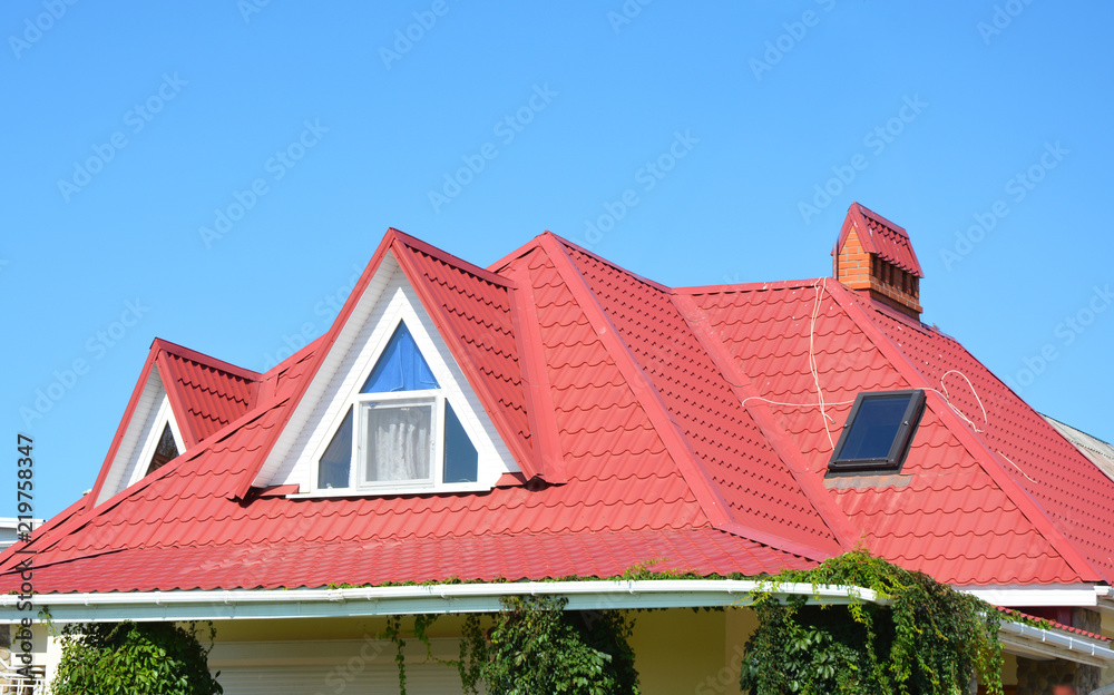 Valley and gable roofing construction with attic windows,  rain gutter, waterproofing. Roof gutter system, skylight window on attic house metal tiles roofing.