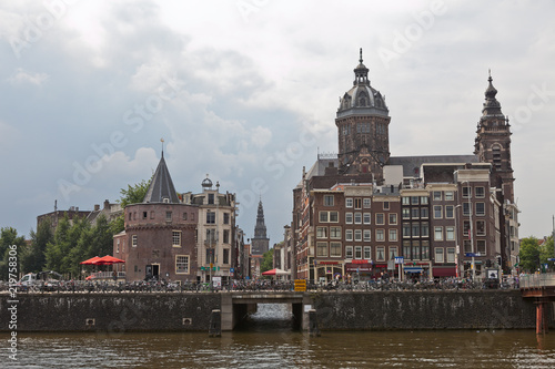 Canal view on the city centre of Amsterdam with a tower and typical canal houses and a church on an overcast day