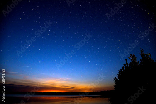 Amazing colorful sky after sunset by the river. Sunset and night sky with a lot of shiny stars.