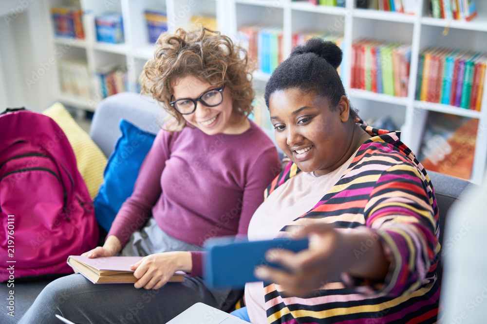 African female student making selfie with her classmate while studying at library African female student making selfie with her classmate while studying at library