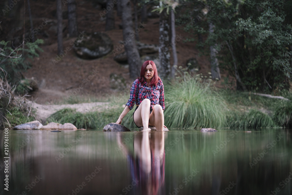 Pretty red haired girl rests by the river. Pretty red haired girl rests by the river.