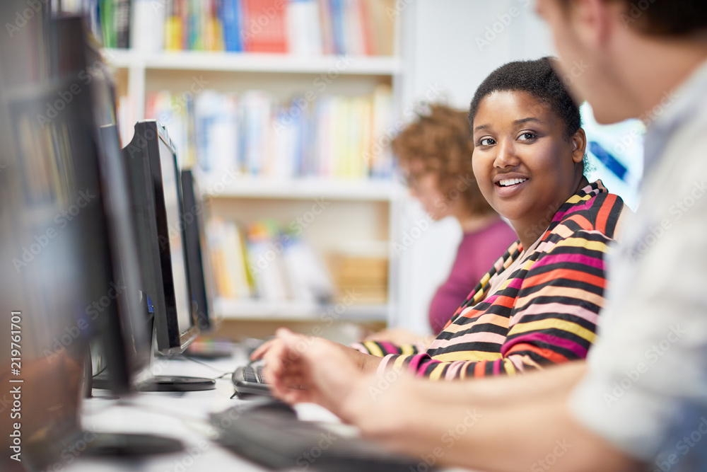 Smiling African female student attending training course in a computer classroom together with her classmates Smiling African female student attending training course in a computer classroom together with her classmates