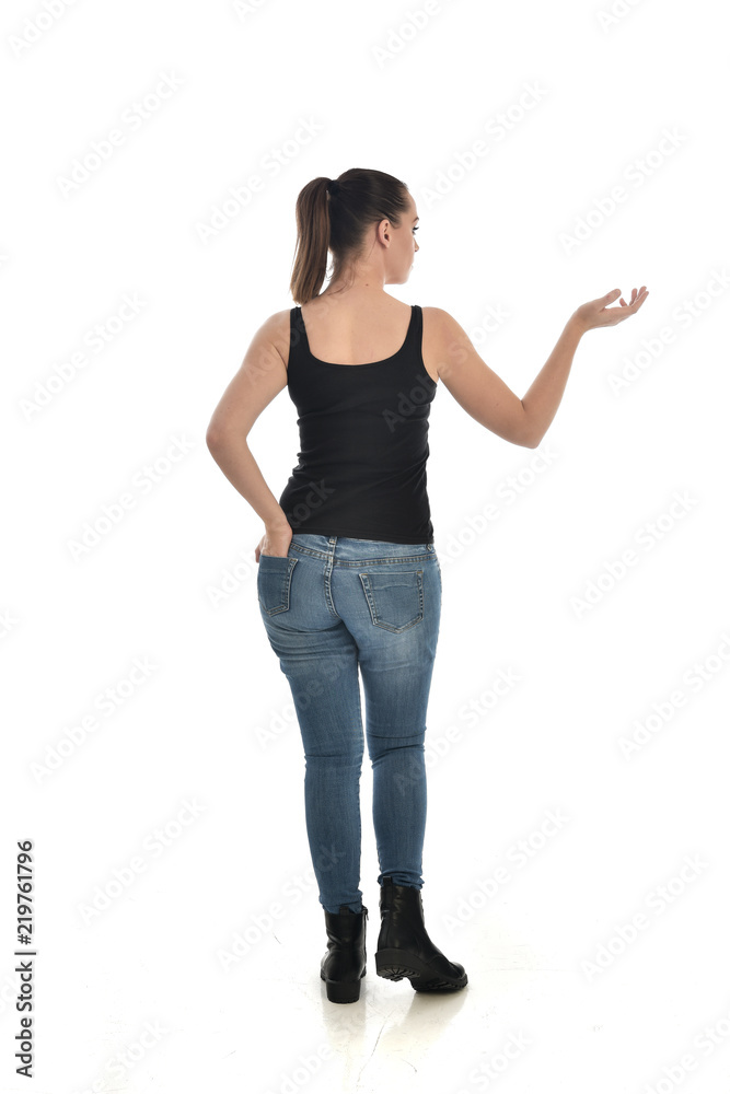 full length portrait of brunette girl wearing black single and jeans. standing pose with back to the camera. isolated on white studio background. full length portrait of brunette girl wearing black single and jeans. standing pose with back to the camera. isolated on white studio background.