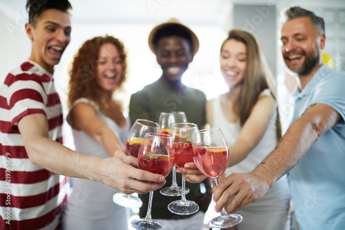 Happy humans clinking with homemade drinks in wineglasses during home gathering