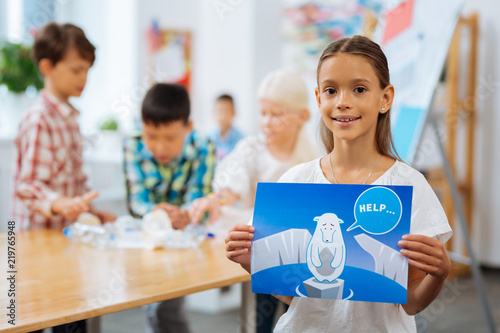 Pole bear. Smiling pretty girl holding a picture in a nahd while standing in a classroom photo